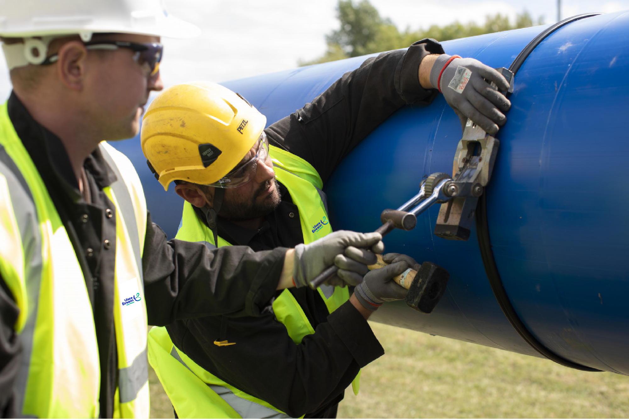 Two Uisce Éireann workers working on a large blue pipe