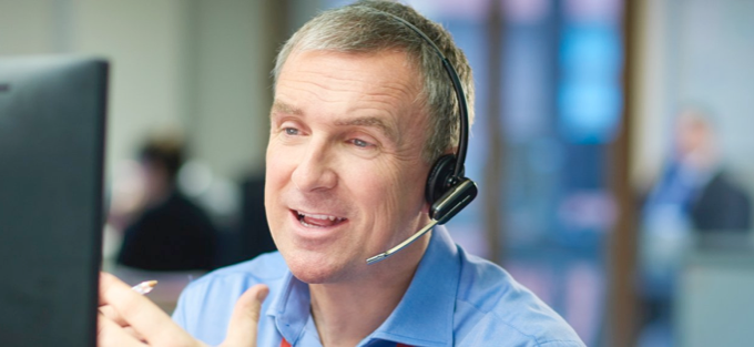 A man with a headset talking to a customer on the phone