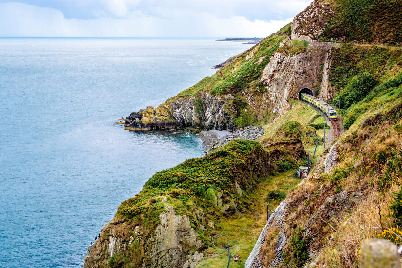 Train going through a tunnel through a mountain by the sea