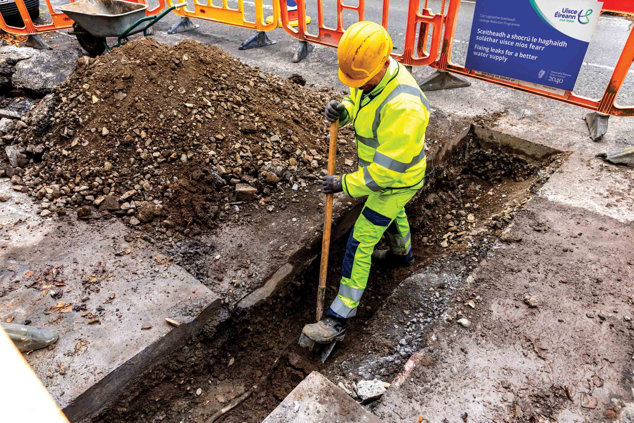 Worker digging a hole on a road