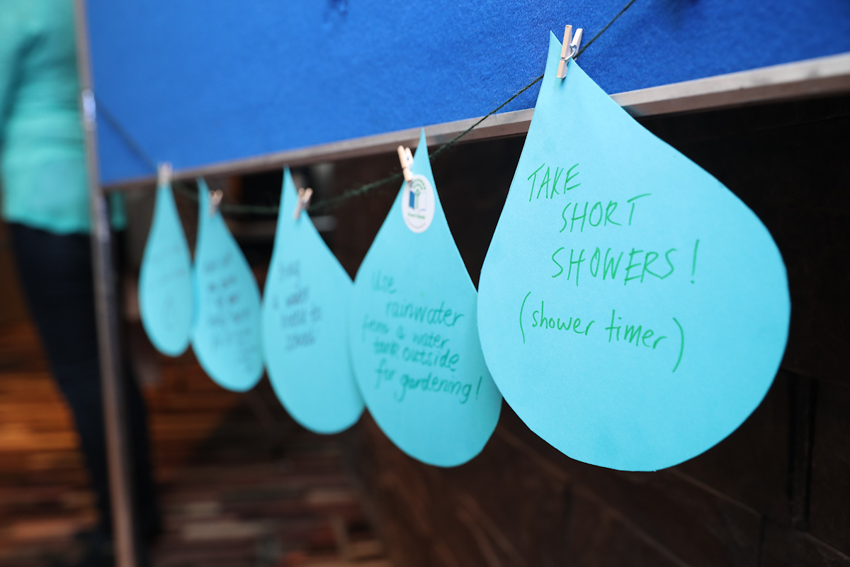 A row of paper cutouts in the shape of drops of water with methods of conserving water written on them