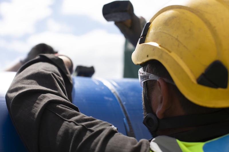 An Uisce Éireann worker working on a large blue pipe