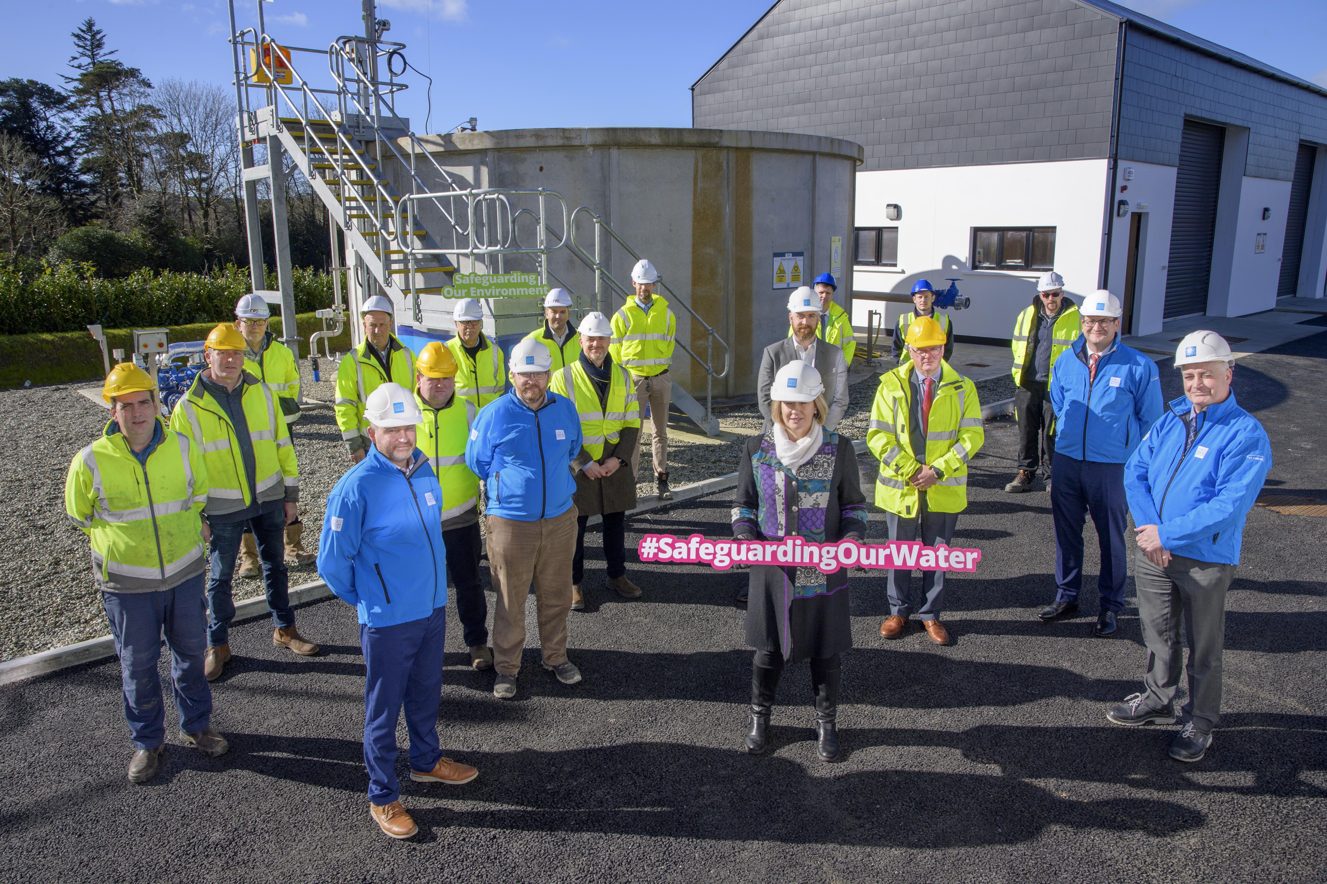 A group of people in hard hats, with one woman holding a sign reading "#SafeguardingOurWater"