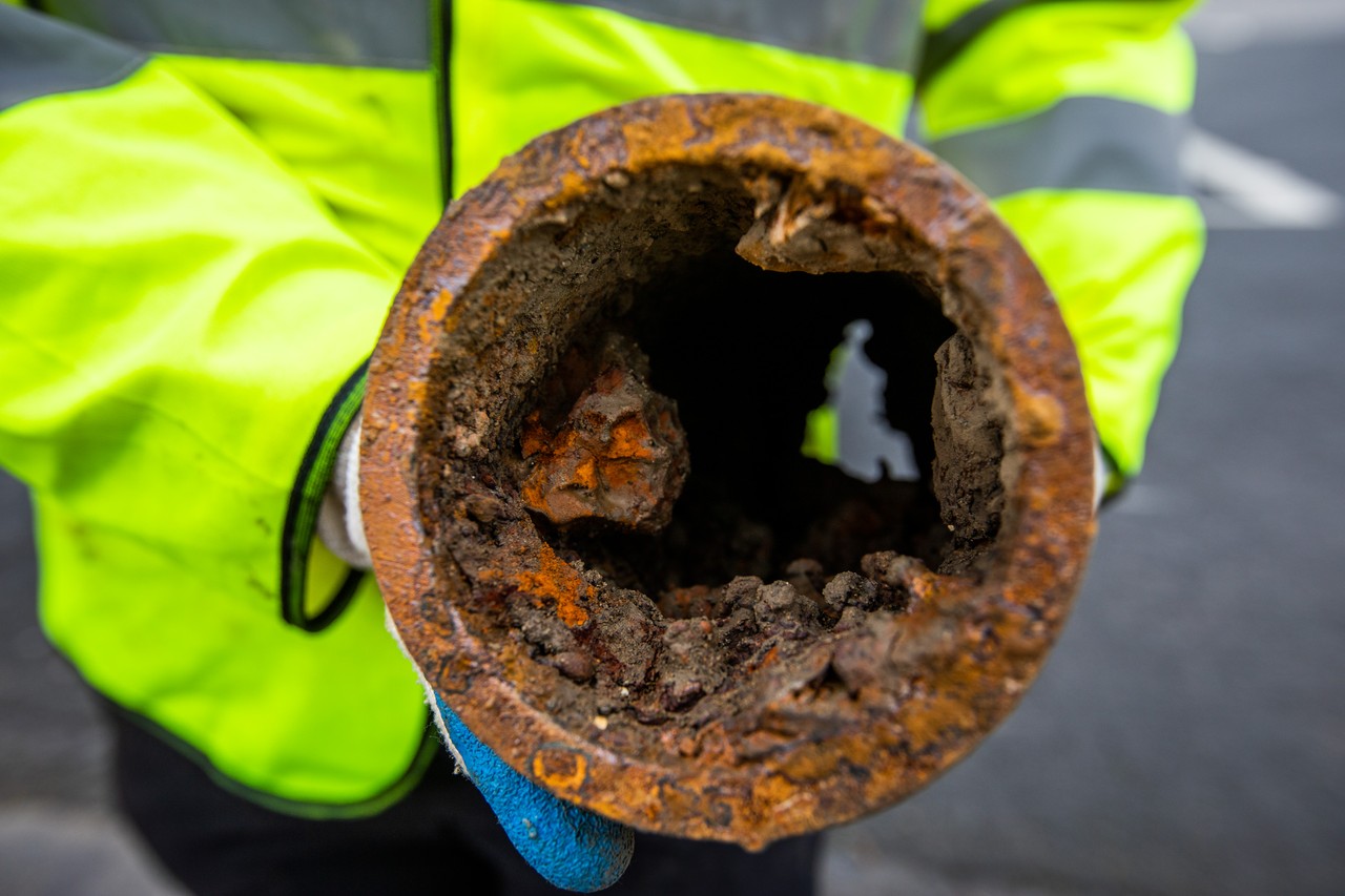 A worker holding an old rusty pipe