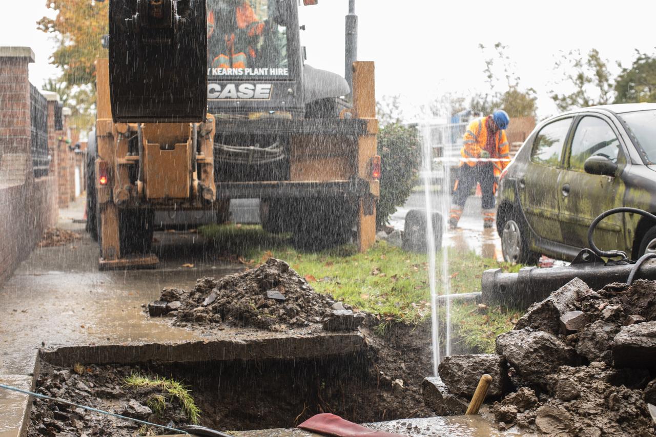 A leaking pipe in the ground spraying water on a construction site