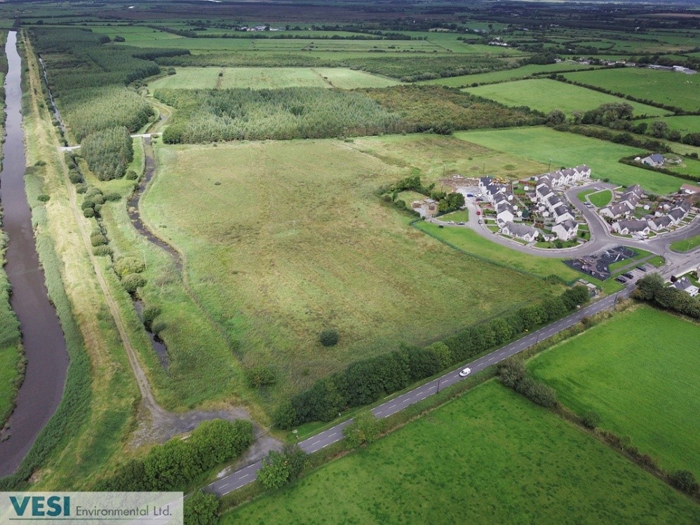 A rural area with many fields, a small river and several rows of houses