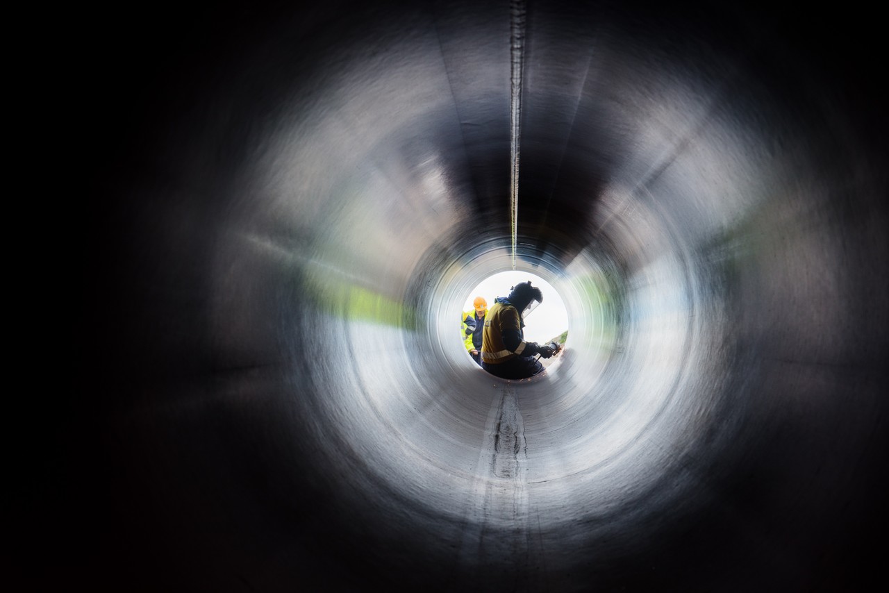 A man sitting at the end of a large metal pipe