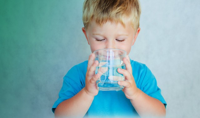 A young boy drinking a glass of water