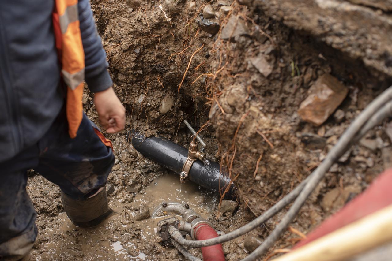 A man standing next to a leaking pipe in the ground