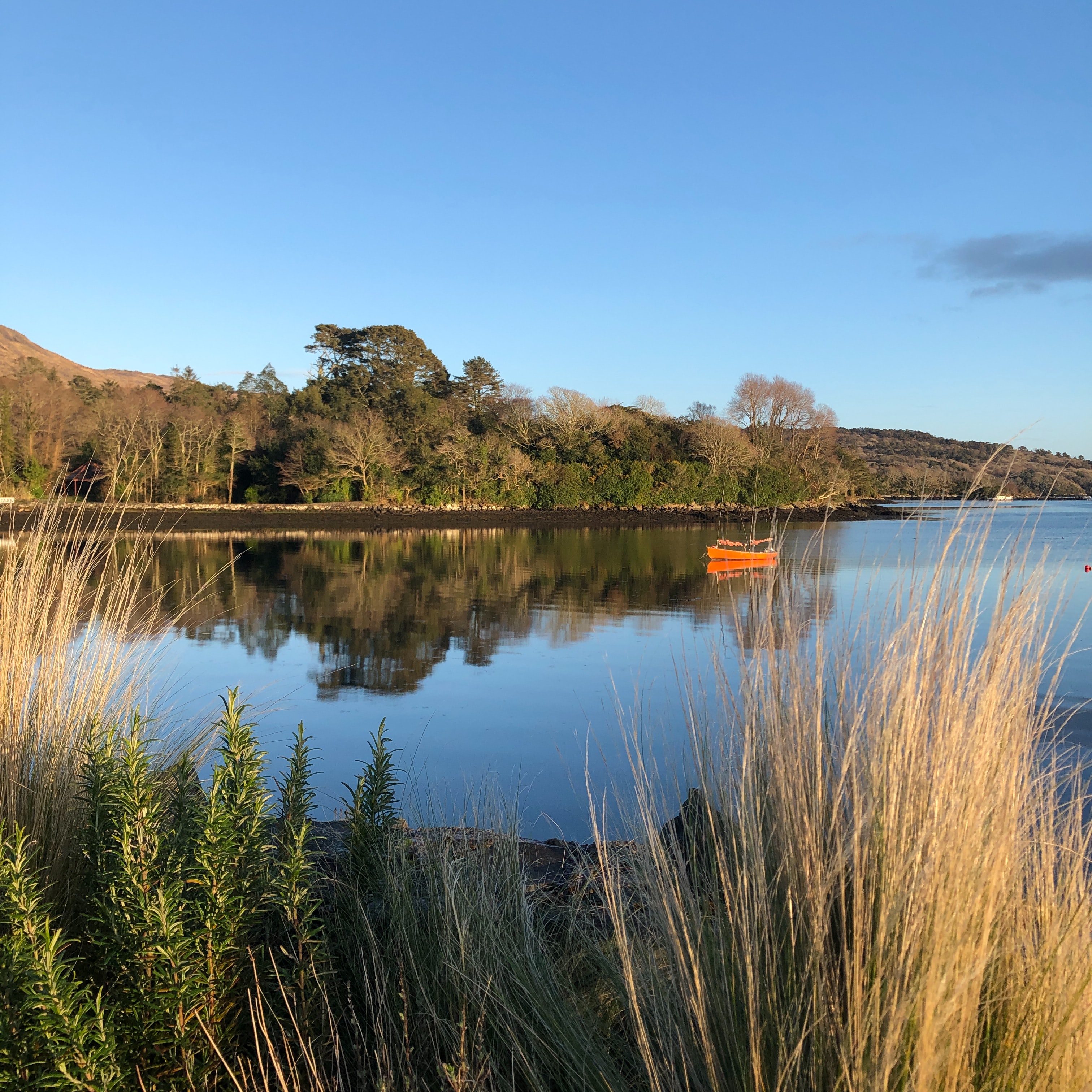 A small orange boat on a lake in the countryside