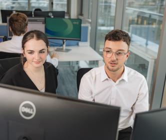 Two graduates looking into a monitor