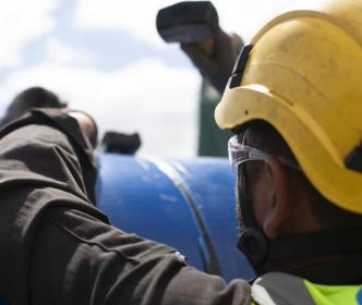 An Uisce Éireann worker working on a large blue pipe