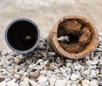 A new clean pipe next to an old damaged and rusty pipe